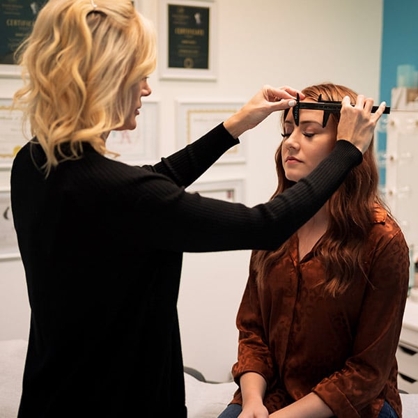 Mary Katz measuring a client's eyebrows before performing permanent makeup at Beauty on Broadway